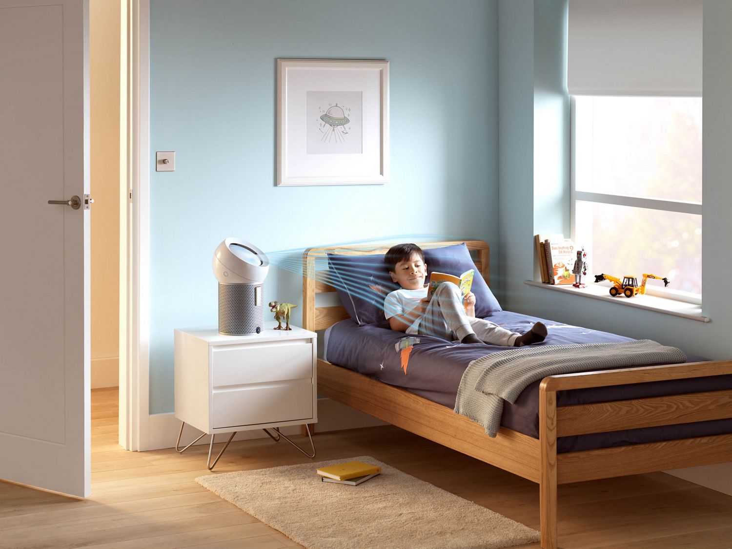 Dyson air purifier used to remove pollen in boy's bedroom as he relaxes and reads in bed